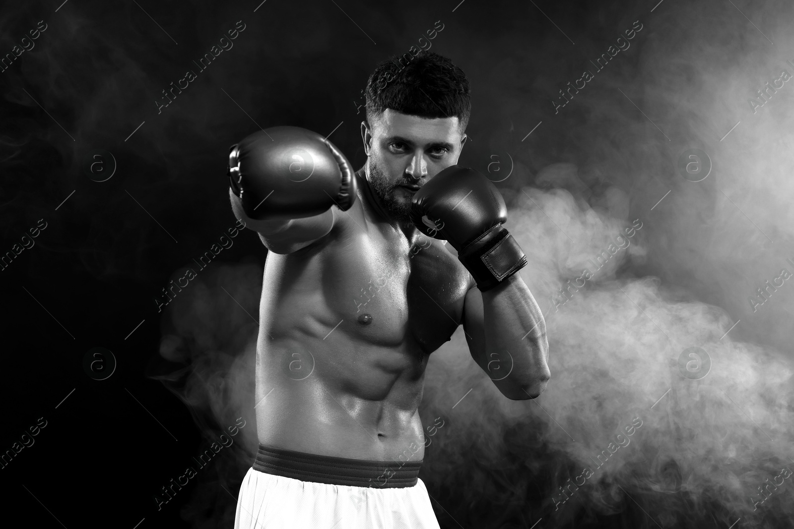 Image of Man wearing boxing gloves fighting in smoke, black-and-white toning