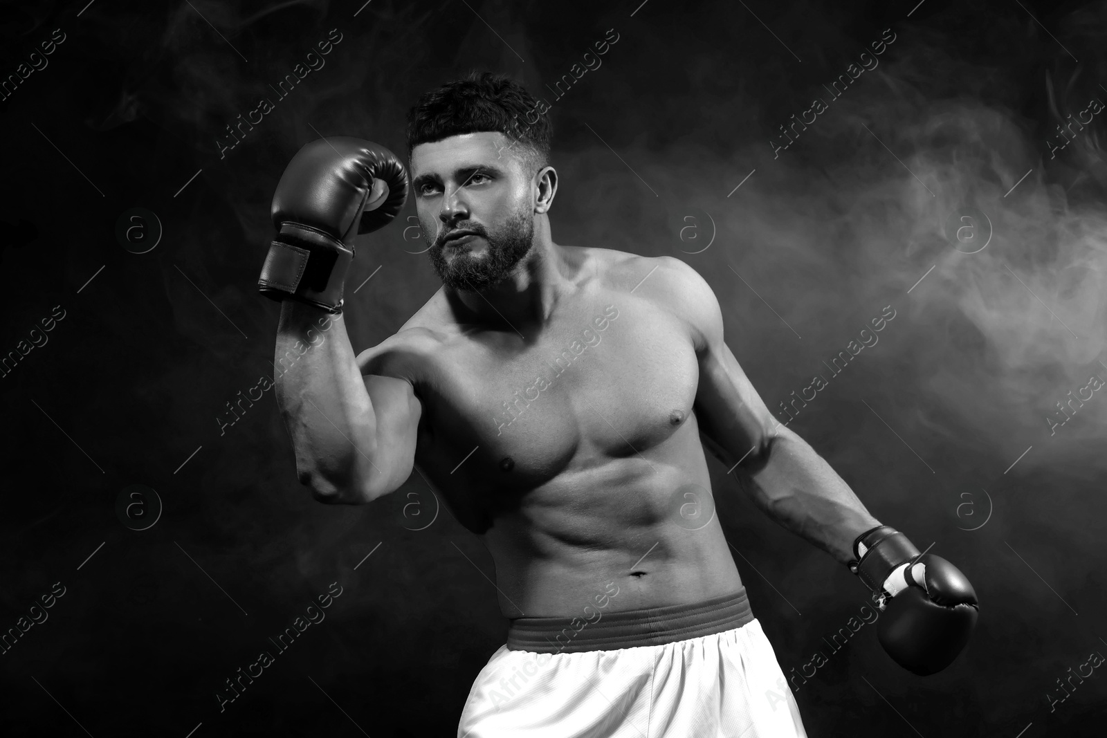 Image of Man wearing boxing gloves fighting in smoke, black-and-white toning