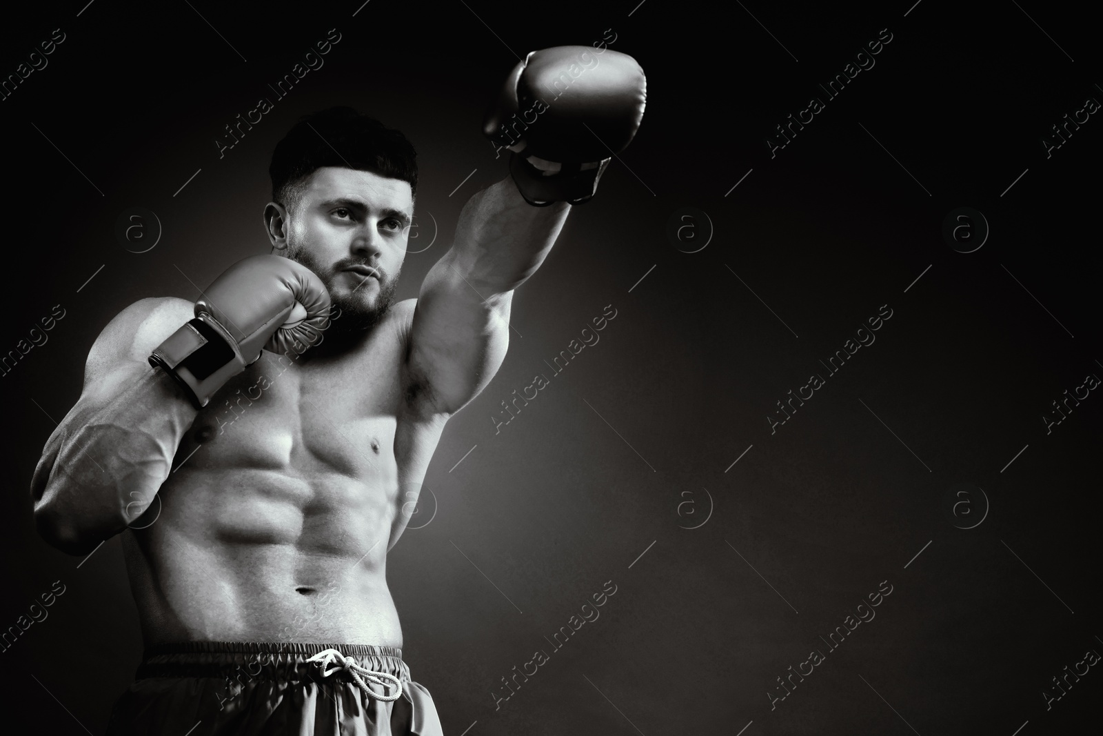 Image of Man in boxing gloves fighting, black-and-white toning. Space for text