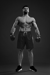 Image of Man in boxing gloves on grey background, low angle view. Black-and-white toning