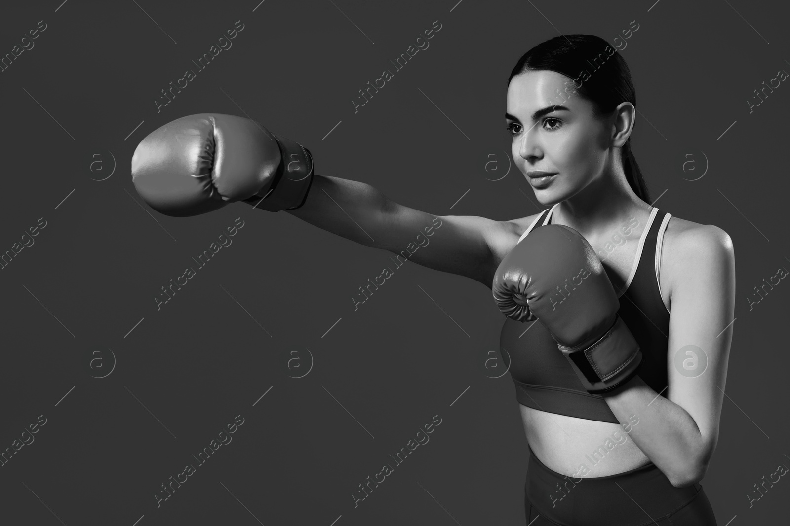 Image of Beautiful woman wearing boxing gloves training, black-and-white toning