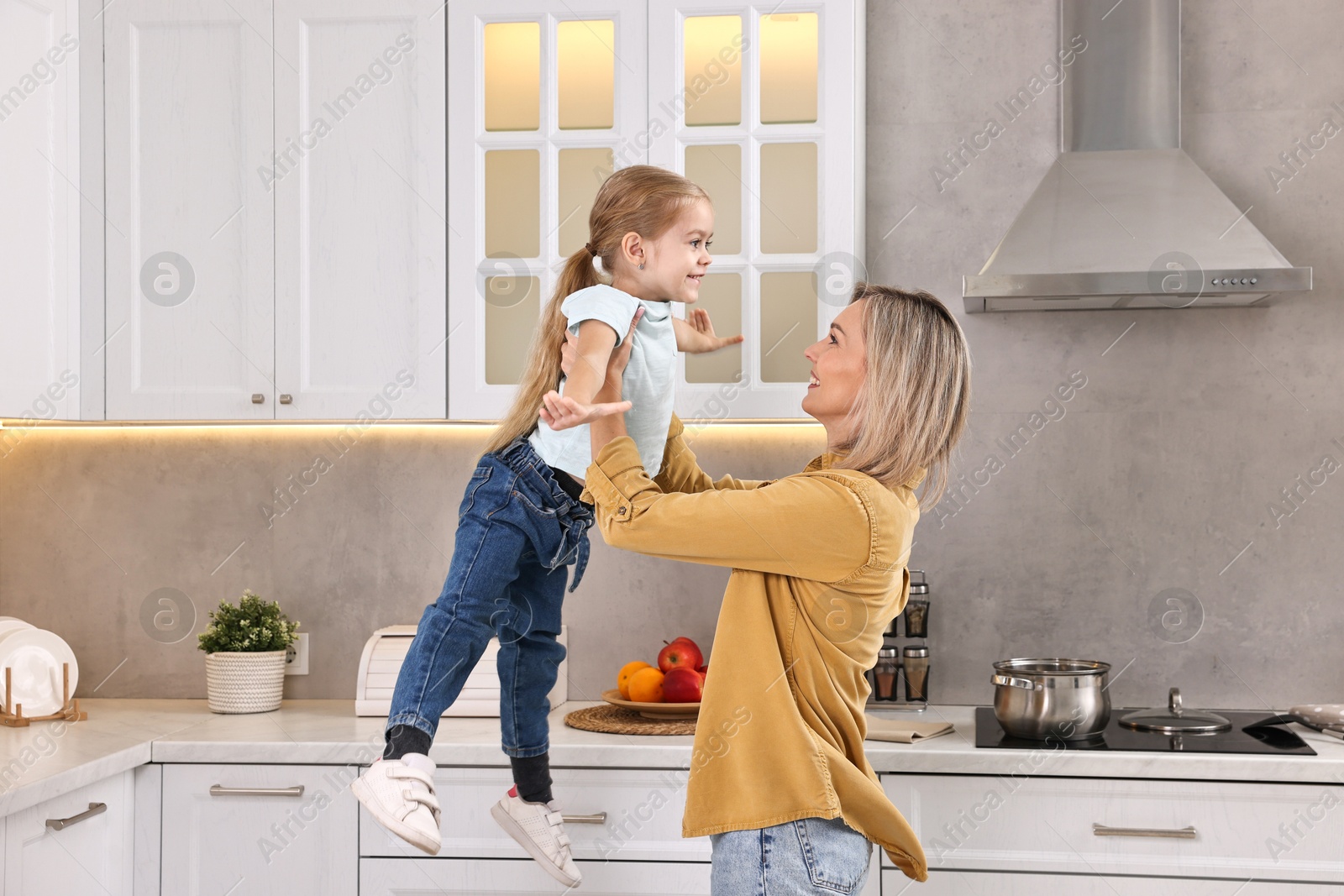 Photo of Happy housewife and her daughter cooking and spending time together in kitchen