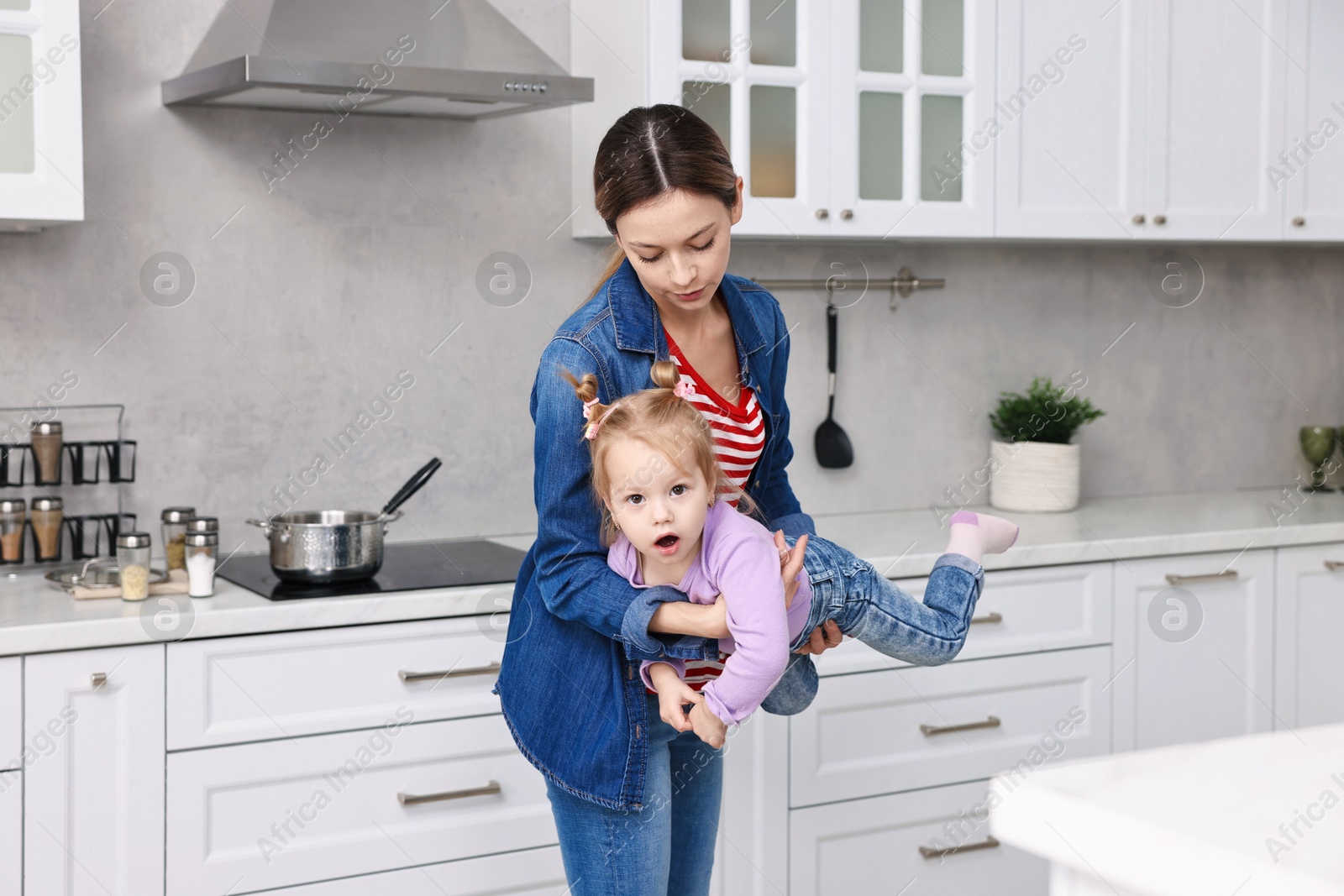 Photo of Housewife playing with her little daughter in kitchen