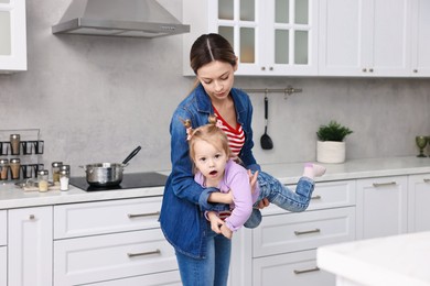 Housewife playing with her little daughter in kitchen