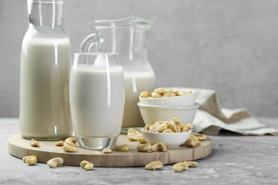 Photo of Glassware with fresh cashew milk and nuts on grey table