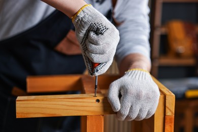 Photo of Carpenter repairing wooden stool in workshop, closeup