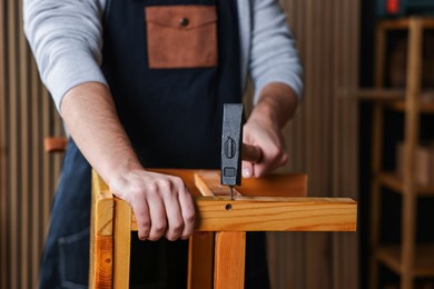 Photo of Carpenter repairing wooden stool in workshop, closeup