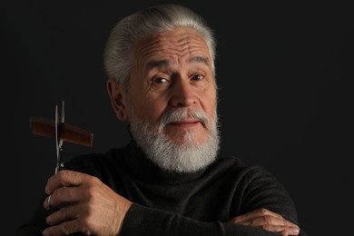 Photo of Bearded man with scissors and comb on dark grey background