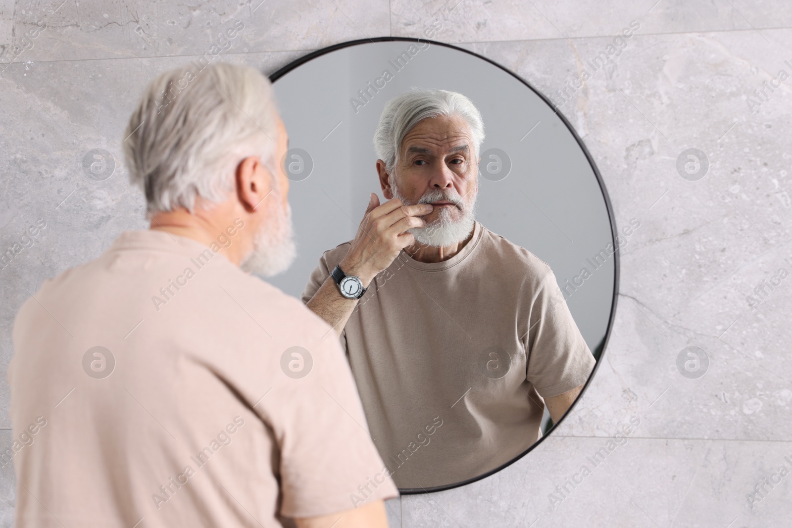 Photo of Bearded senior man near mirror in bathroom