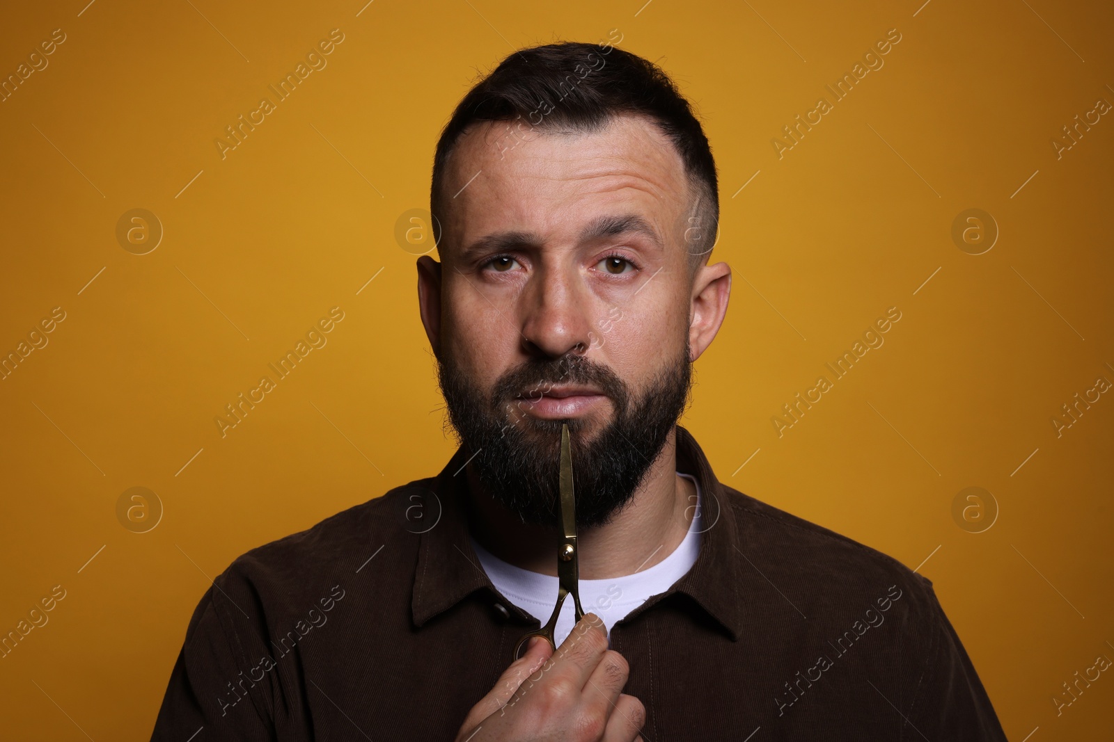 Photo of Bearded man with scissors on orange background