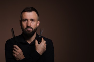 Photo of Bearded man holding comb and scissors on brown background, space for text