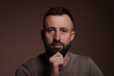 Photo of Portrait of handsome bearded man on brown background