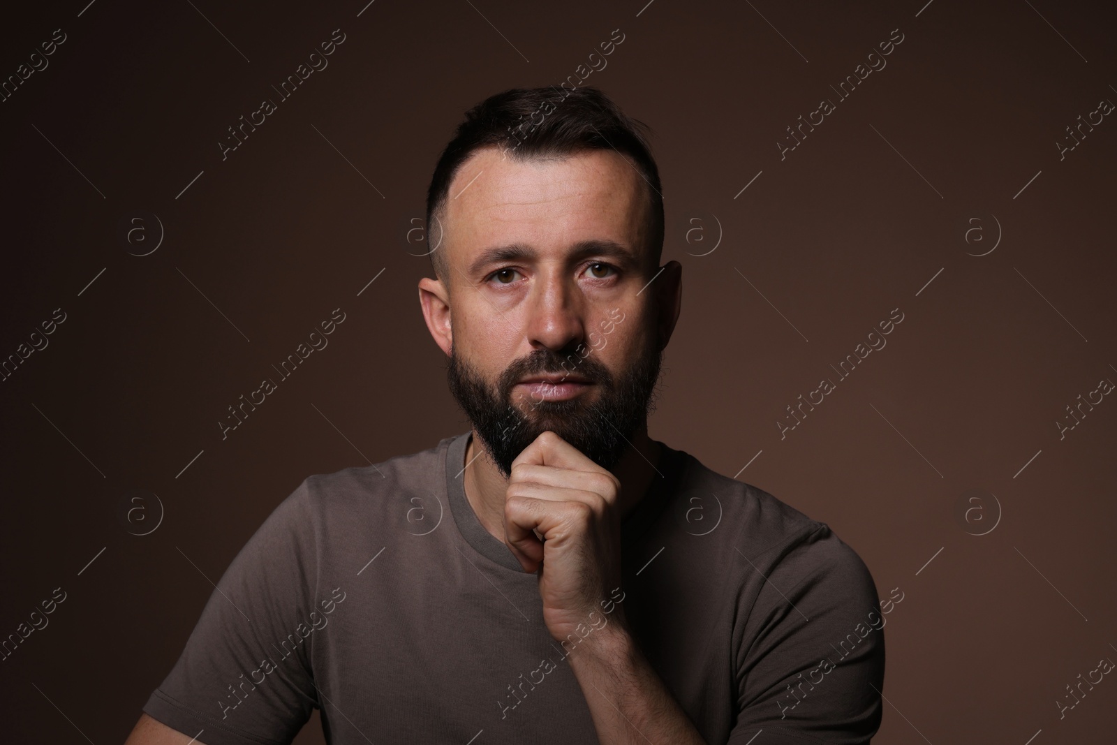 Photo of Portrait of handsome bearded man on brown background