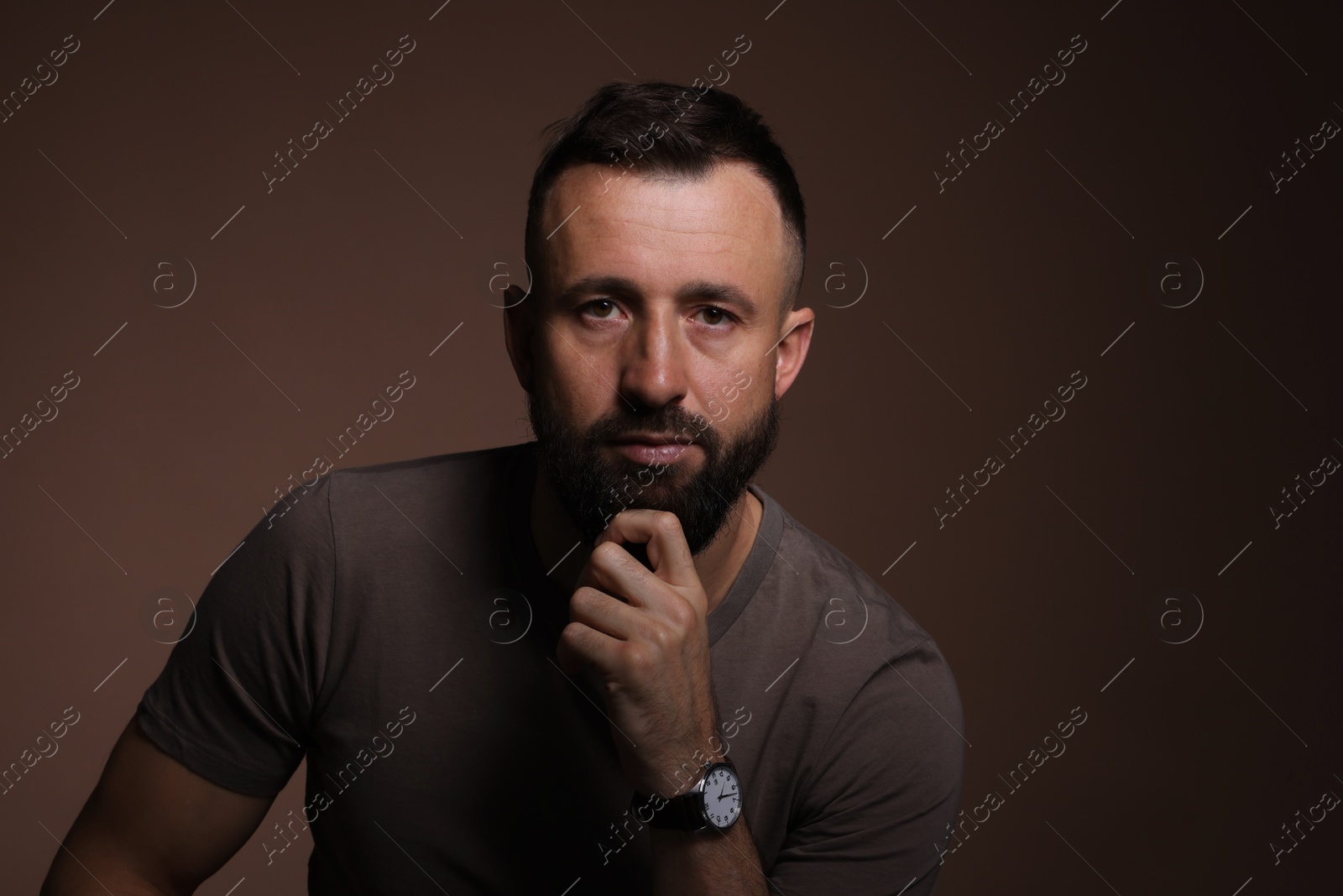 Photo of Portrait of handsome bearded man on brown background