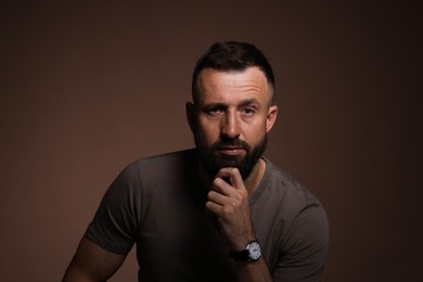 Photo of Portrait of handsome bearded man on brown background