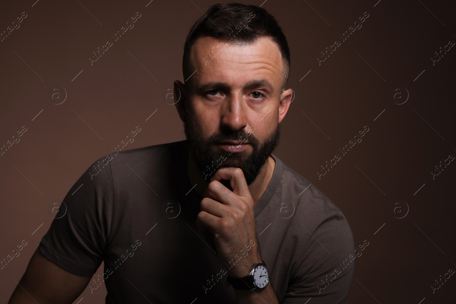 Photo of Portrait of handsome bearded man on brown background