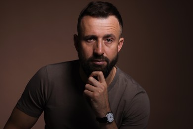 Photo of Portrait of handsome bearded man on brown background