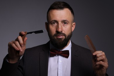 Photo of Bearded man holding blade and scissors on grey background