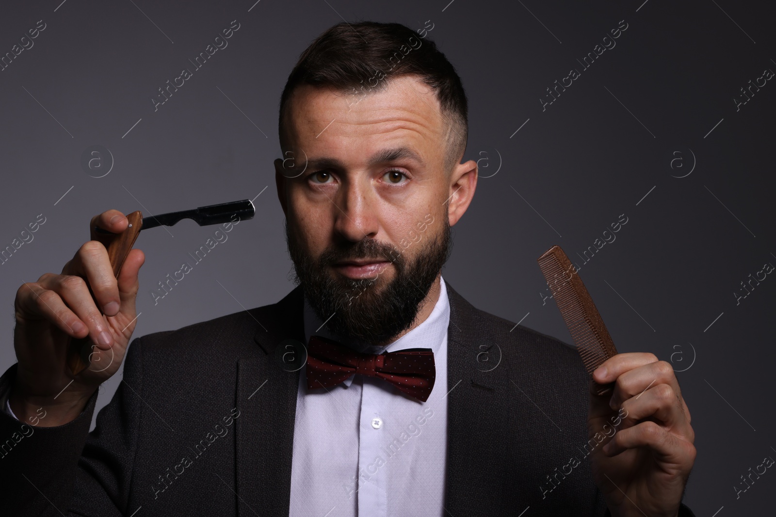 Photo of Bearded man holding blade and scissors on grey background