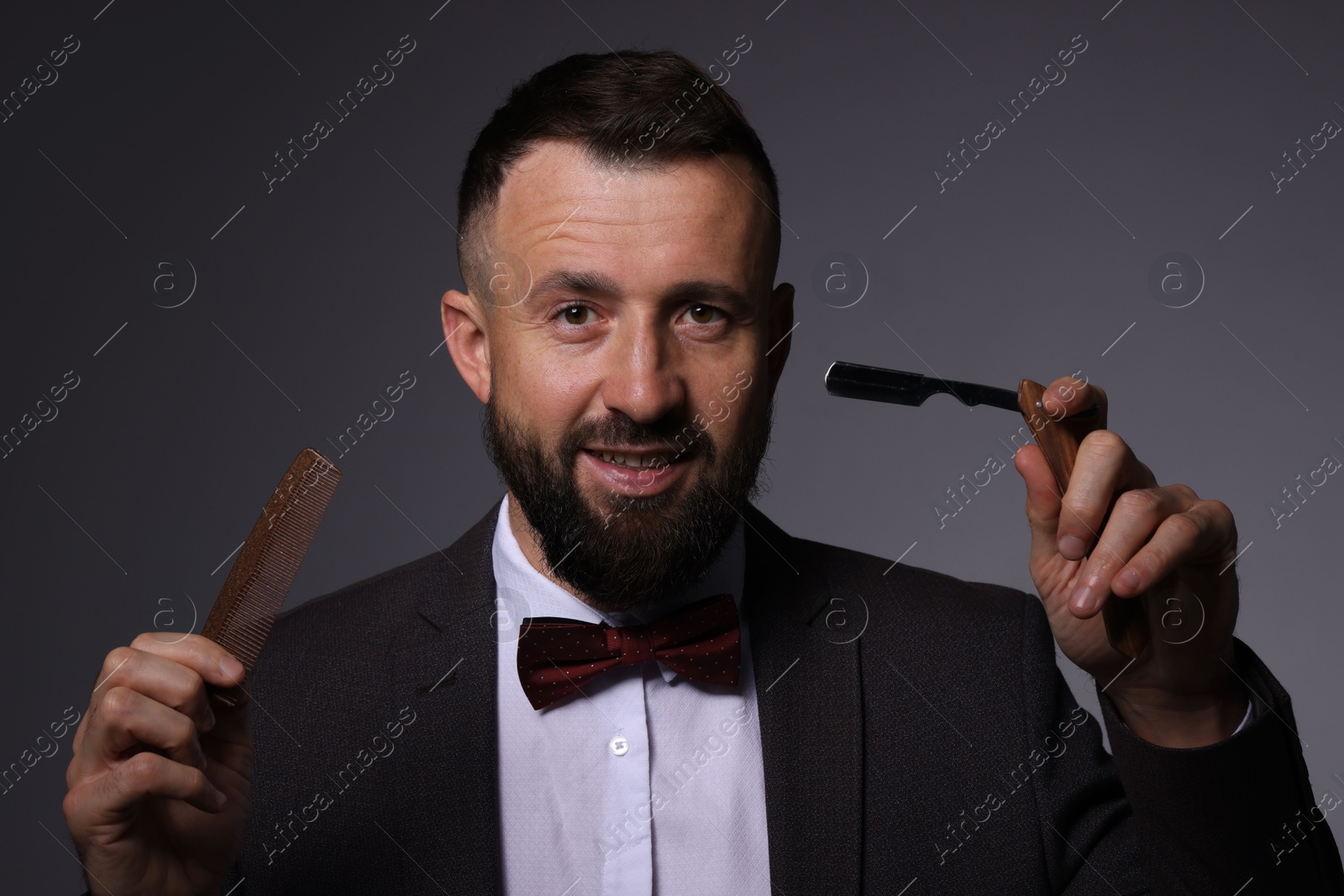 Photo of Bearded man holding blade and scissors on grey background