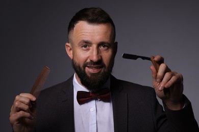 Photo of Bearded man holding blade and scissors on grey background