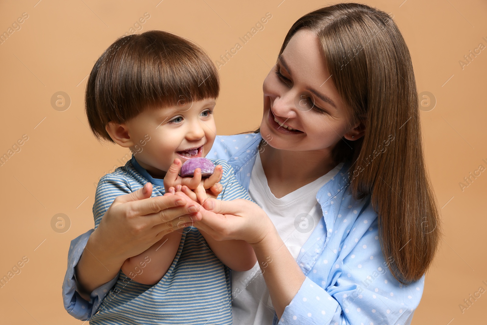 Photo of Mother and baby eating tasty mochi on brown background