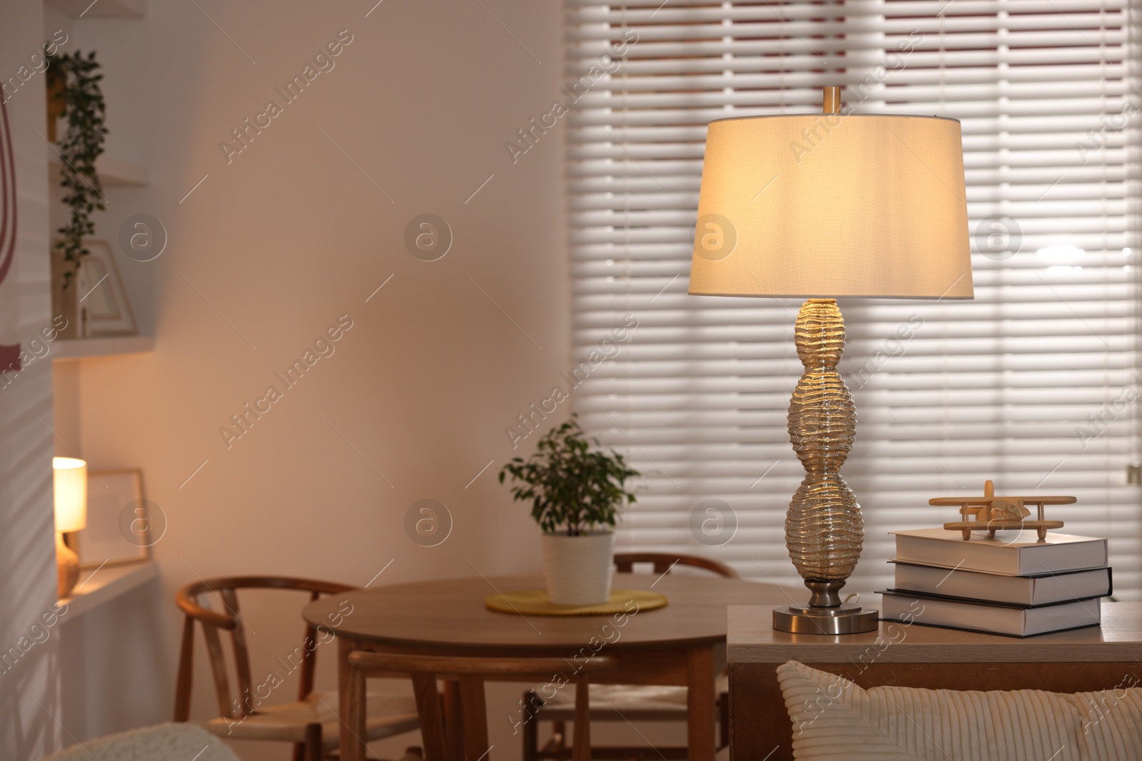 Photo of Beautiful night lamp on chest of drawers and other furniture indoors. Space for text