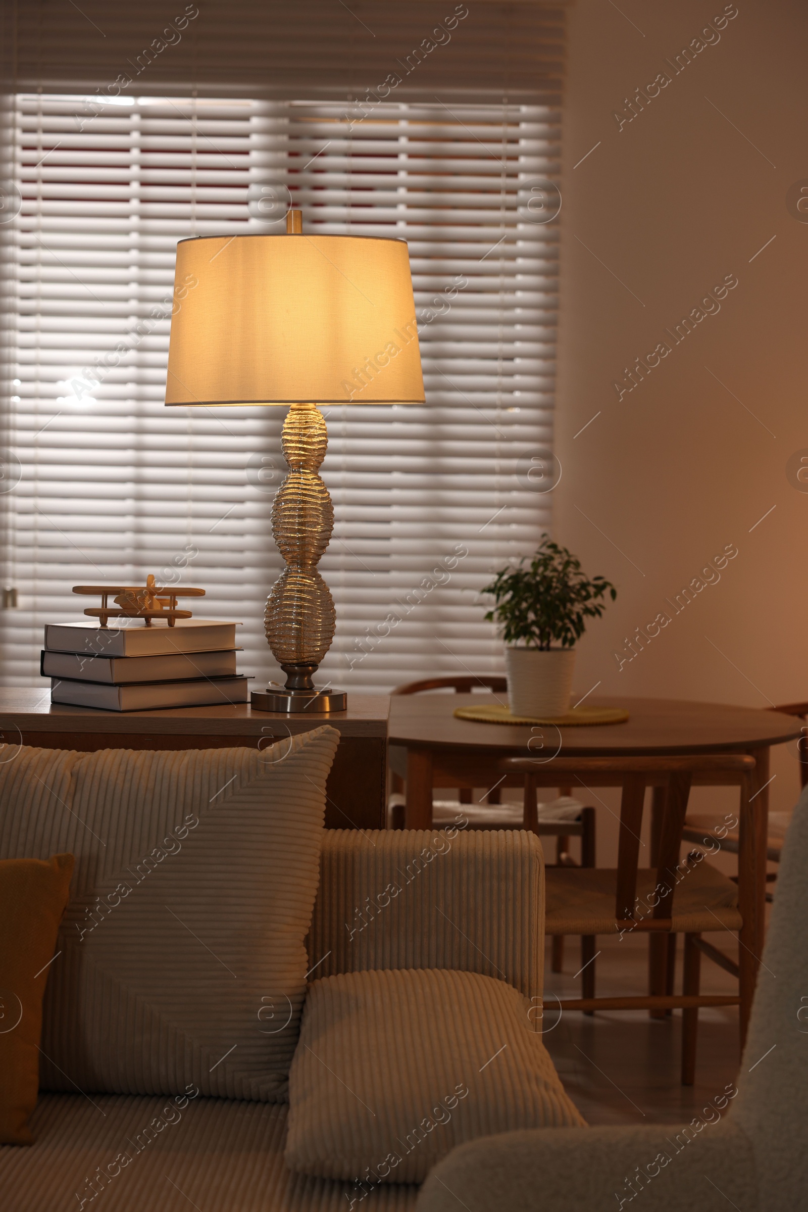 Photo of Beautiful night lamp on chest of drawers and other furniture indoors