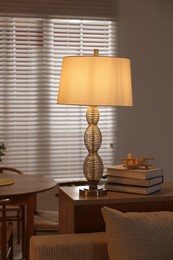 Photo of Beautiful night lamp, stack of books and airplane model on chest of drawers indoors