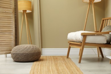 Photo of Stylish knitted pouf and armchair in room