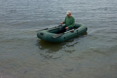 Photo of Man fishing with rod from inflatable rubber boat on river