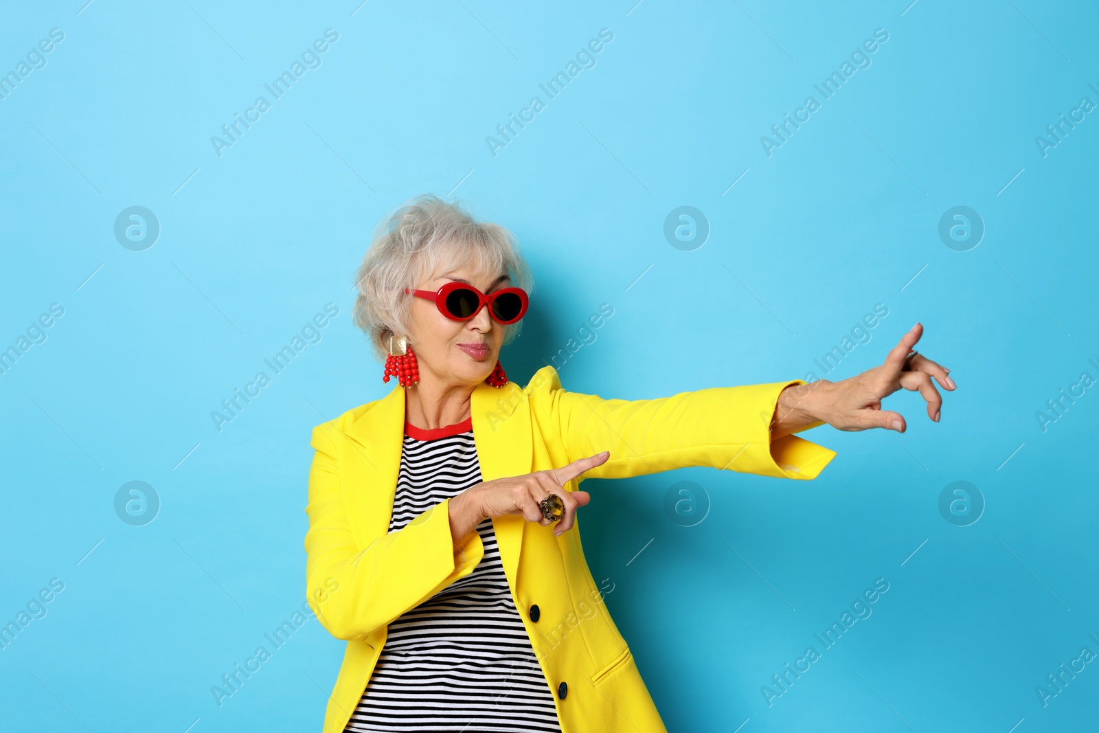 Photo of Portrait of cool grandmother in yellow jacket on light blue background