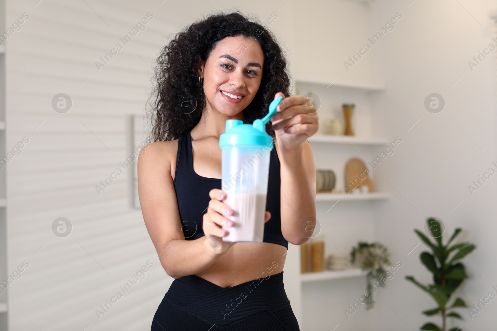 Photo of Beautiful woman with protein shake at home, selective focus