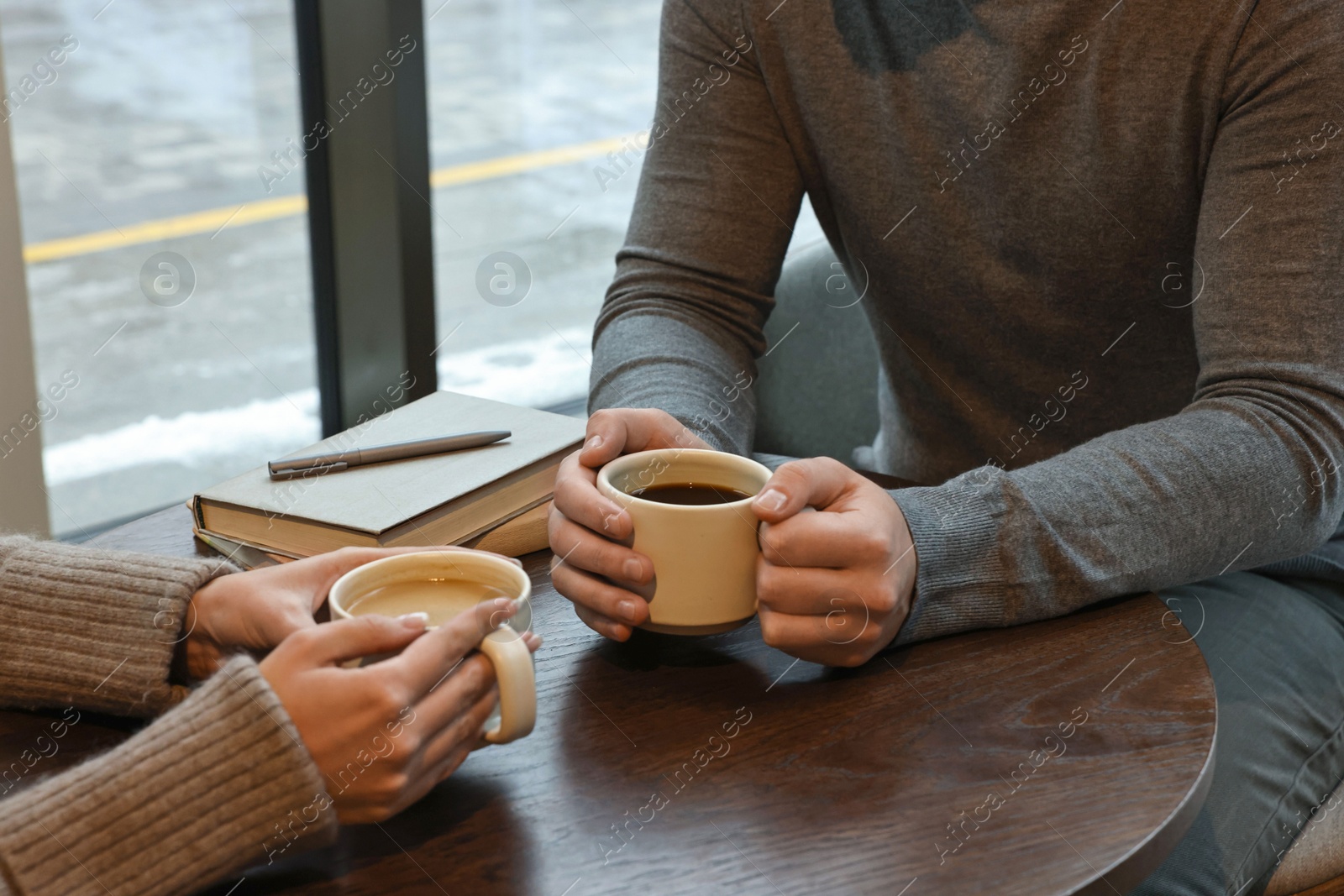 Photo of Colleagues having coffee break at wooden table in cafe, closeup