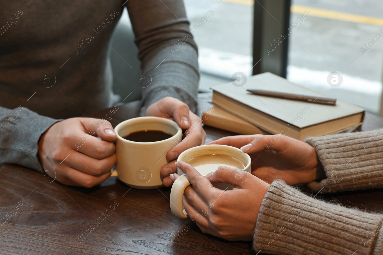 Photo of Colleagues having coffee break at wooden table in cafe, closeup