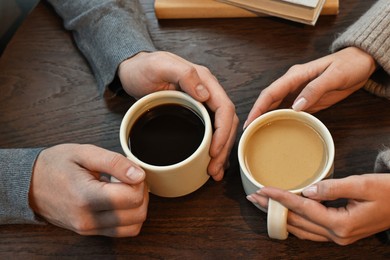 Photo of Colleagues having coffee break at wooden table, closeup