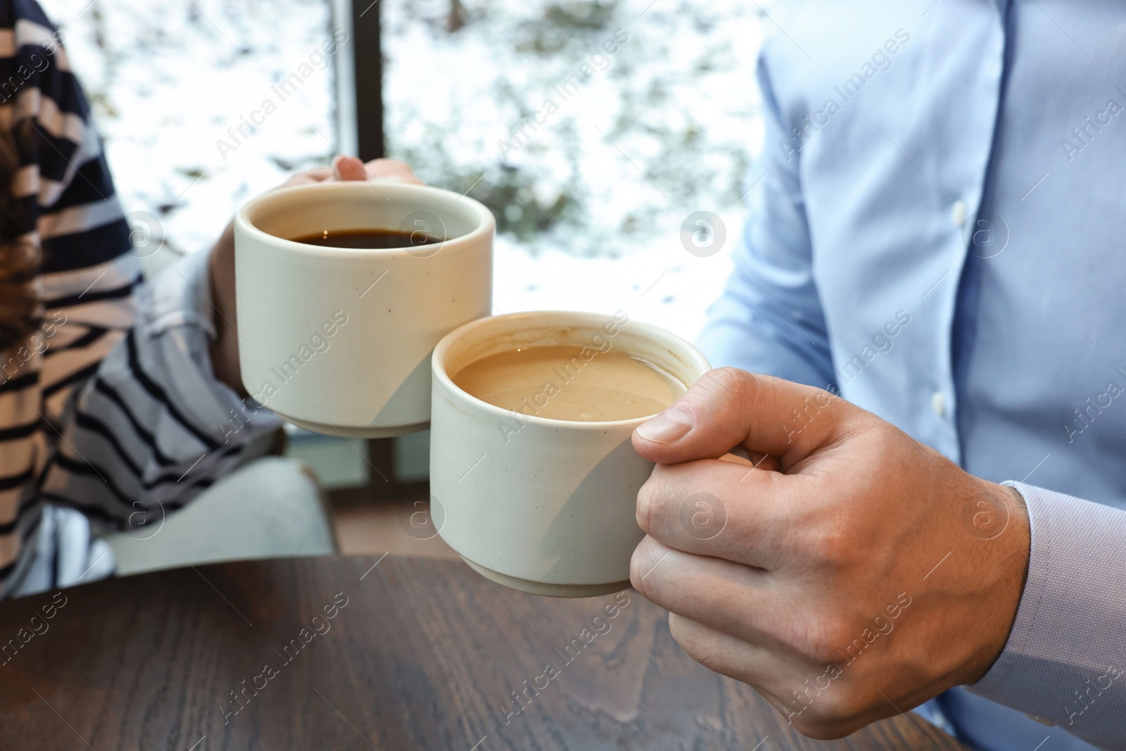 Photo of Colleagues having coffee break at wooden table in cafe, closeup