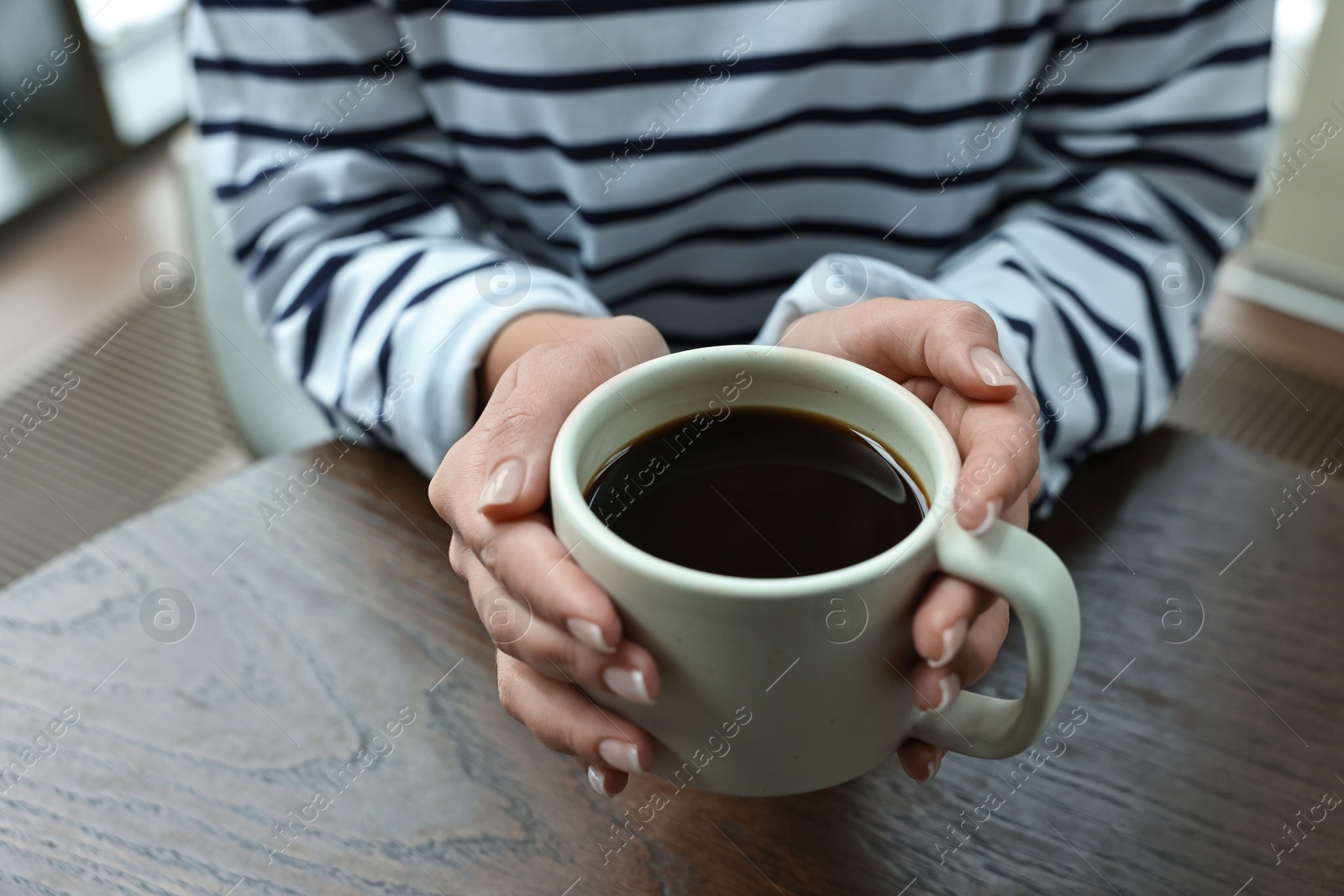 Photo of Woman having coffee break at wooden table in cafe, closeup