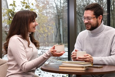 Photo of Happy colleagues talking during coffee break at wooden table in cafe