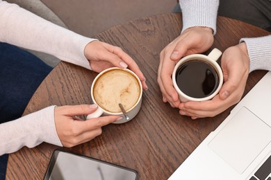 Photo of Colleagues having coffee break at wooden table in cafe, above view