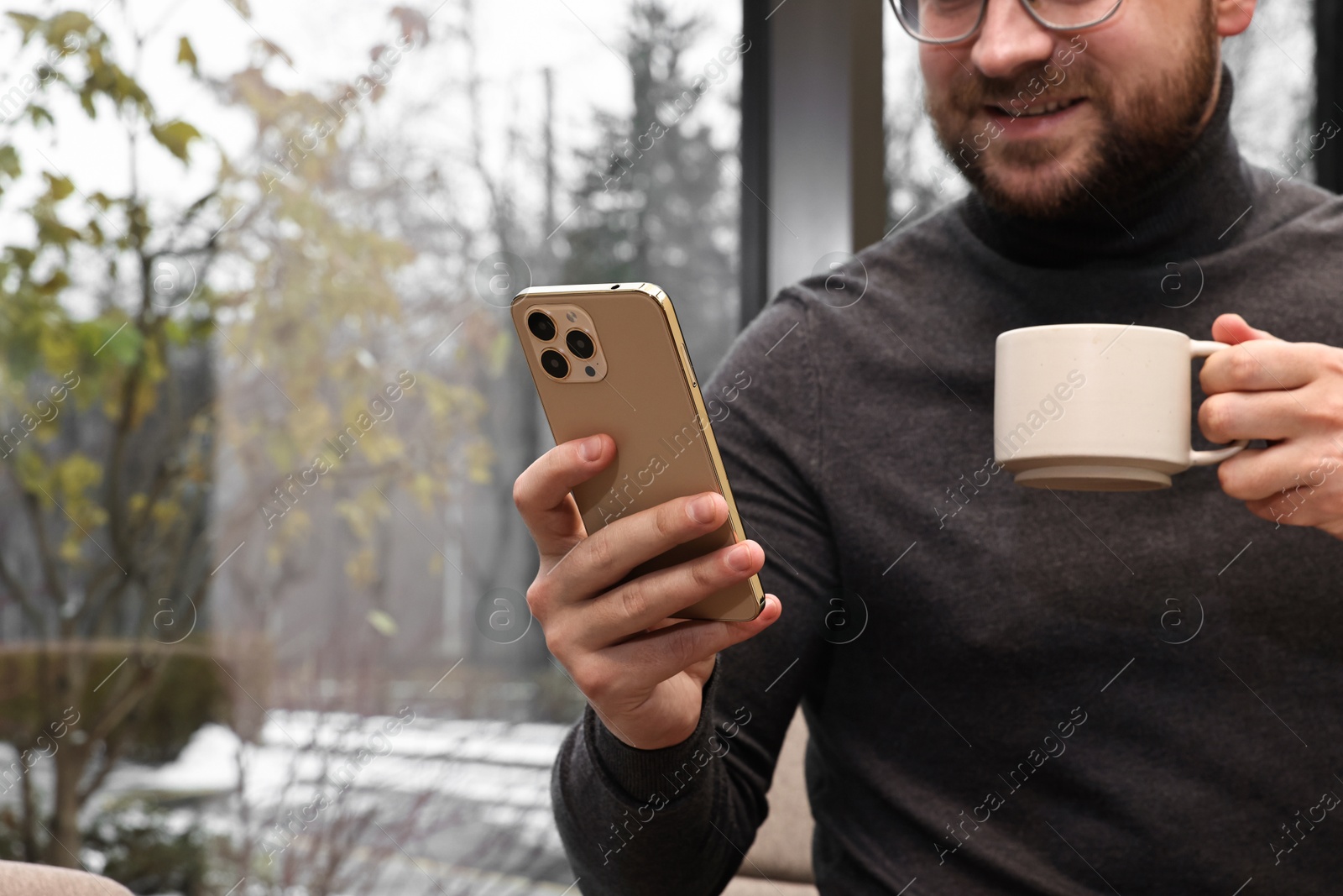 Photo of Smiling businessman with smartphone having coffee break in cafe, closeup. Space for text