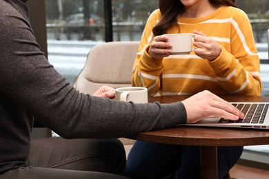 Colleagues having coffee break at wooden table in cafe, closeup