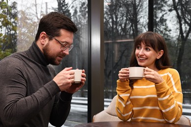 Photo of Happy colleagues talking during coffee break at wooden table in cafe