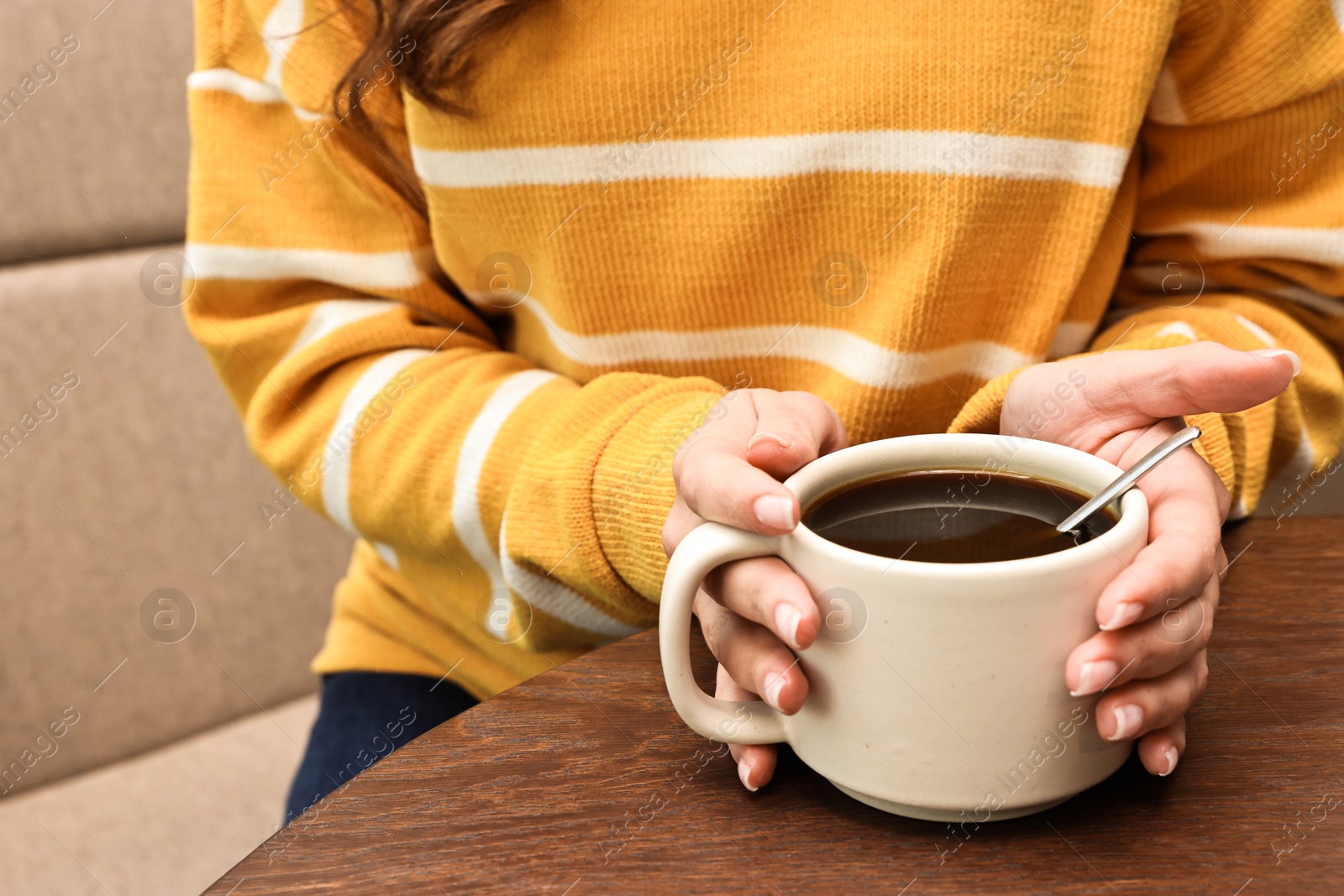 Photo of Woman having coffee break at wooden table in cafe, closeup