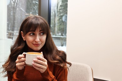 Beautiful woman having coffee break in cafe. Space for text