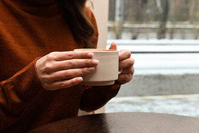 Photo of Woman having coffee break at wooden table in cafe, closeup