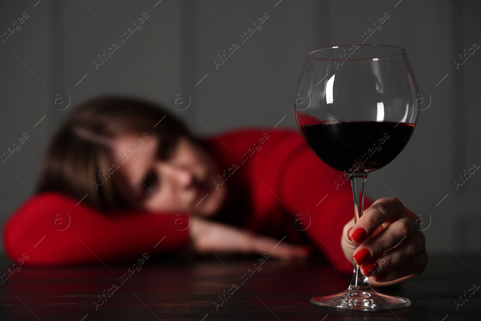 Photo of Alcohol addiction. Woman with glass of red wine at wooden table indoors, selective focus