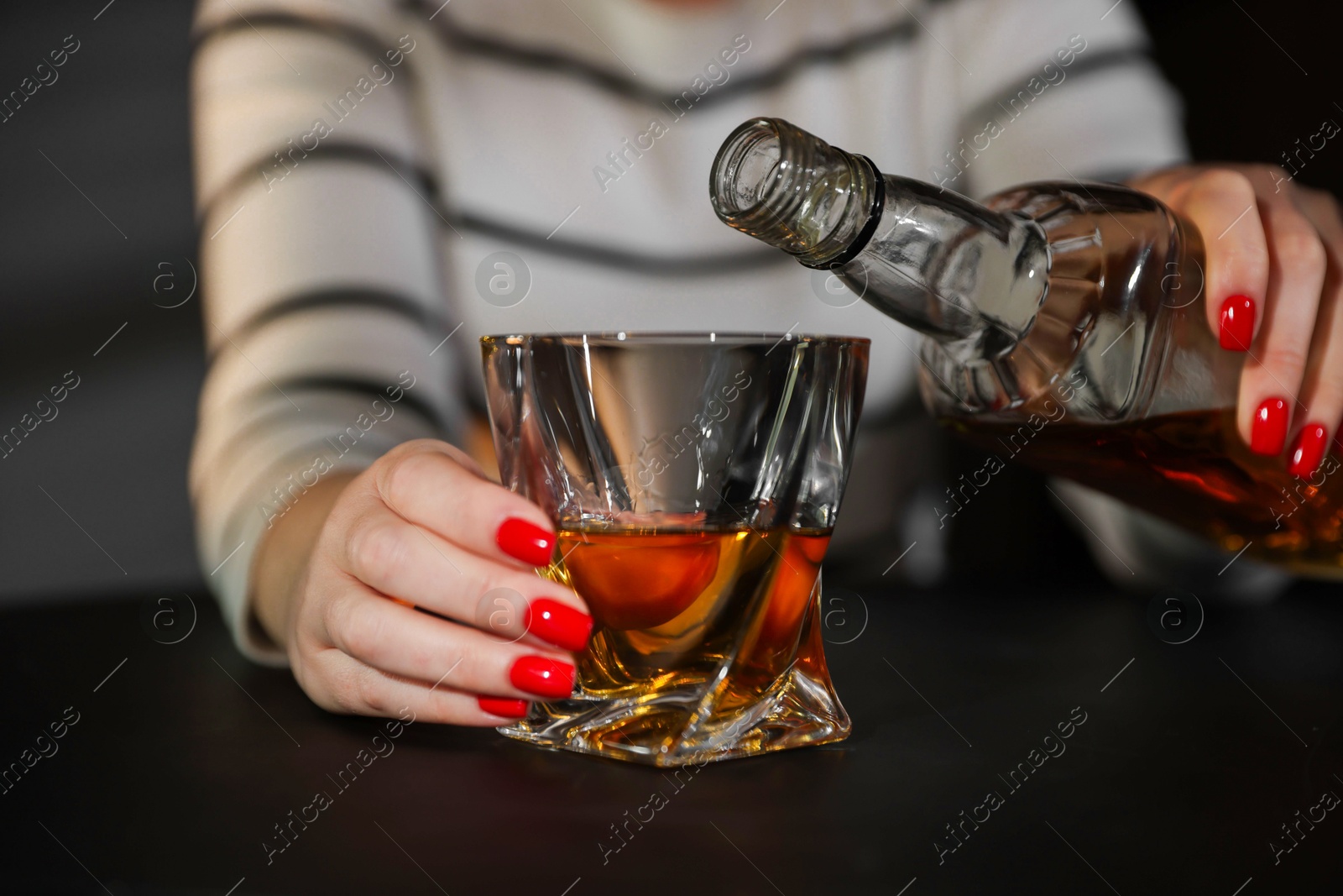 Photo of Alcohol addiction. Woman with glass of whiskey and bottle indoors, closeup