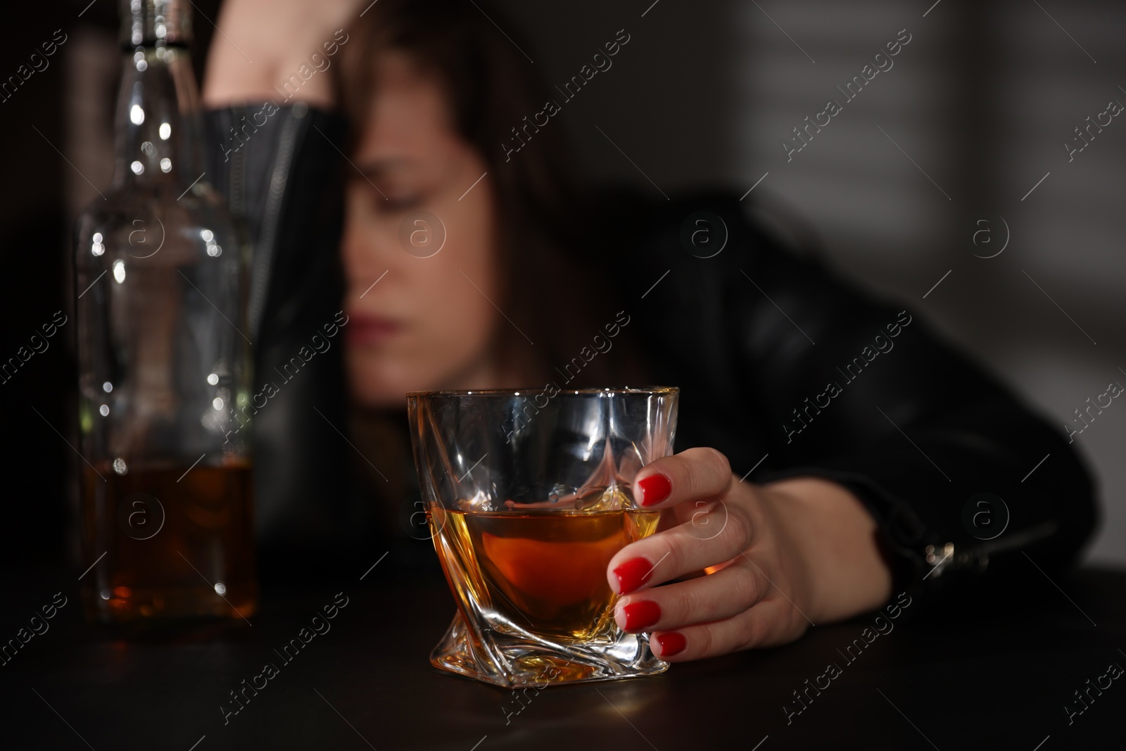 Photo of Alcohol addiction. Woman with glass of whiskey at table, selective focus