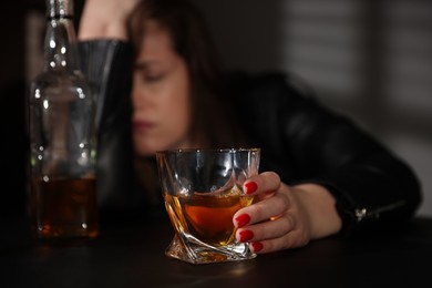 Photo of Alcohol addiction. Woman with glass of whiskey at table, selective focus